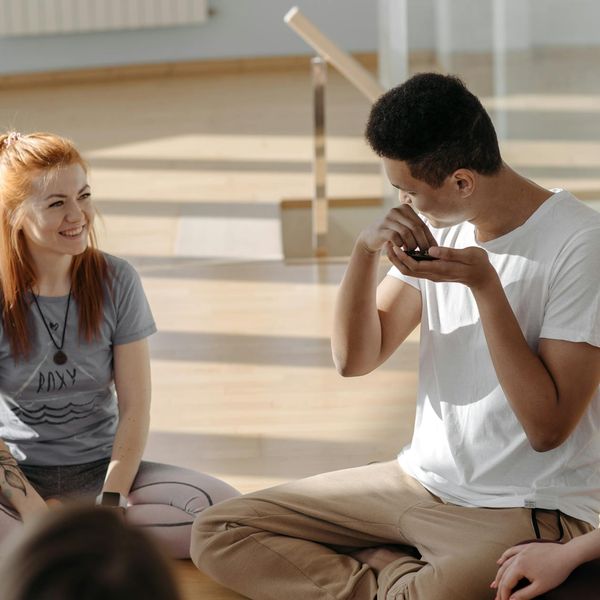 A group of diverse people sitting comfortably on yoga mats in a bright studio.